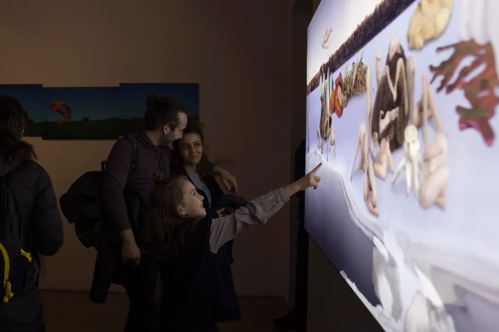 Visitors viewing a panoramic backlit artwork in a dark exhibition space